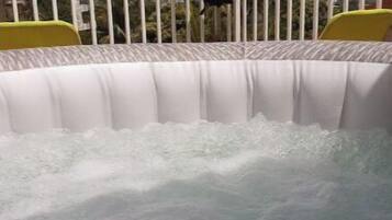 Un bain à remous avec une barrière blanche et une chaise jaune.