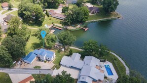 Una vista aerea di una zona residenziale sul lago, con case, un molo e una piscina.