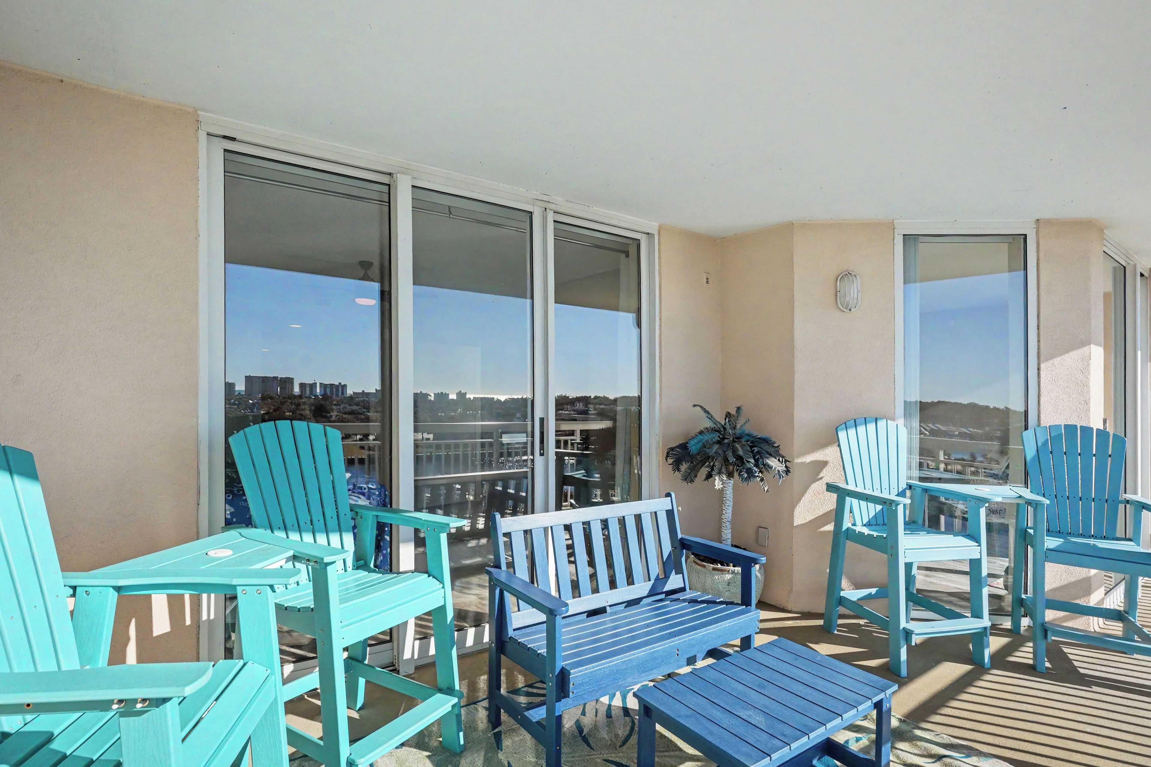 Un balcon donnant sur la ville, aménagé avec des chaises bleues et une table.