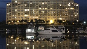A large hotel with multiple floors and balconies, reflecting in the water.