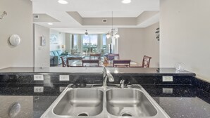 A modern kitchen with a double sink, granite countertop, and a view of the dining area.