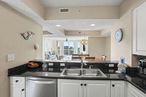A modern kitchen with a black countertop, white cabinets, and a visible dishwasher.
