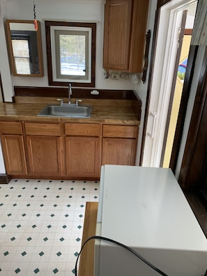 A kitchen with wooden cabinets, a sink, and a window. - Wild Grape Cottage - 8 Miles from Two Harbors and Lake Superior (Two Harbors)