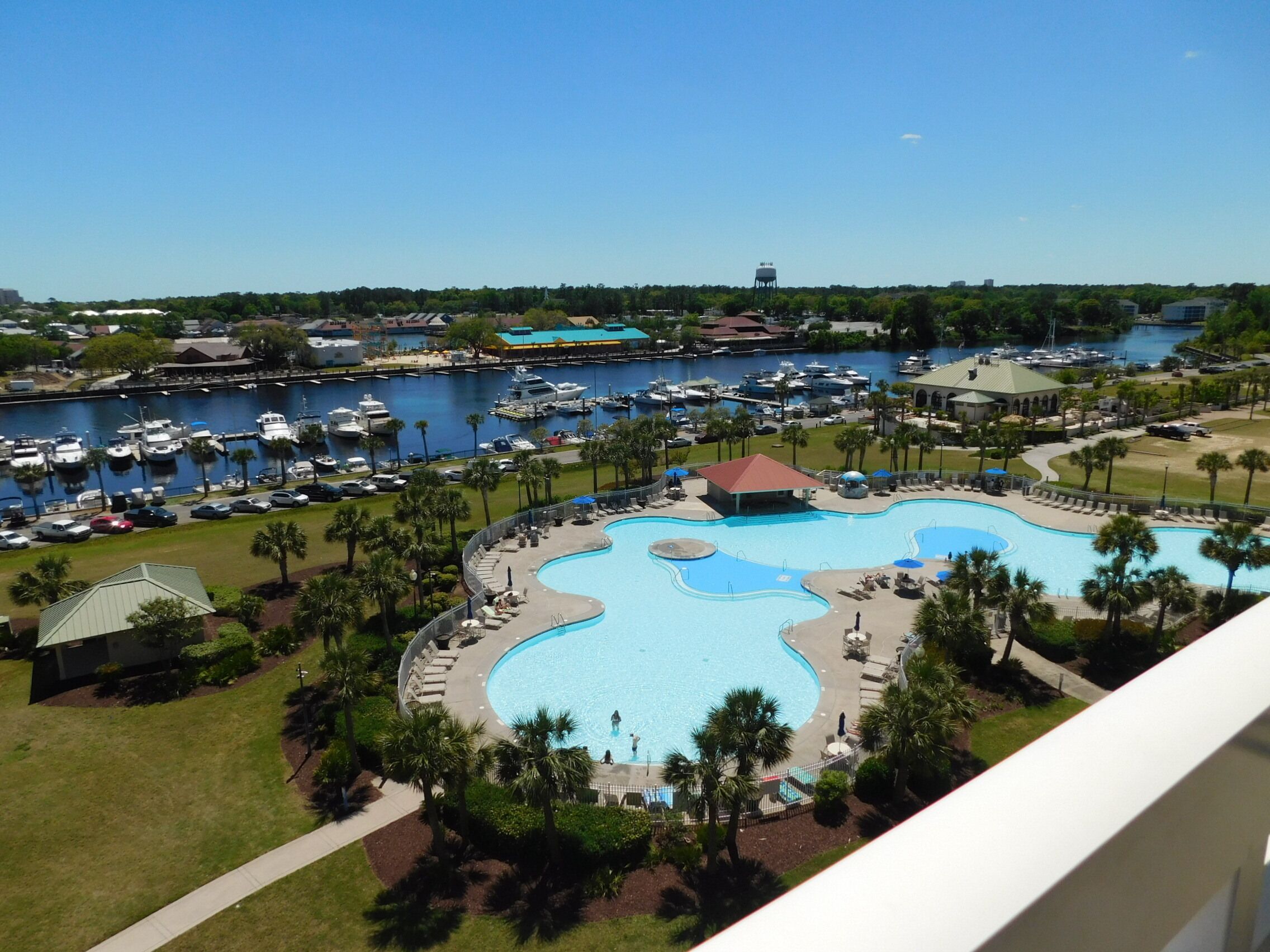 A marina with boats, a swimming pool, and a building with a red roof.