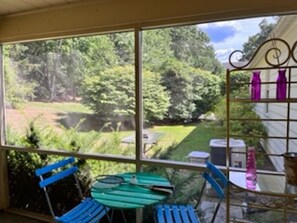 Enjoy a serene view of the lush garden from the large window, paired with a simple, functional space featuring a green table and two chairs.