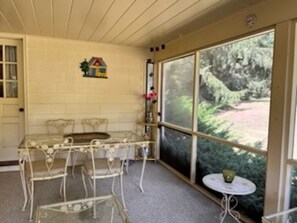 Enjoy a peaceful view of the garden from the large window in this serene room, featuring a dining table, chairs, and a wall-mounted shelf.