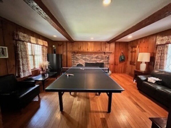 Enjoy a game of ping pong in this spacious room with a fireplace, sofa, and armchair.