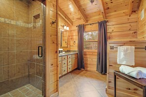 A wooden cabin bathroom with a shower, vanity, and a towel rack.