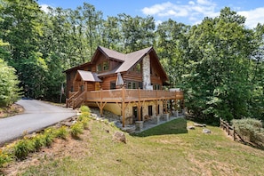A log cabin with a deck, surrounded by trees. - Pinch Me - Mr Lake Lure Vacation Rentals (Lake Lure)