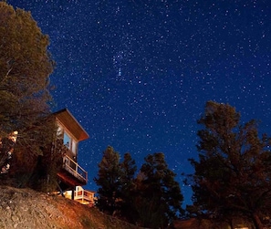 A cabin with a balcony overlooking a starry night sky.