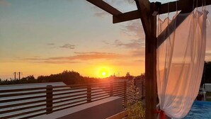 A wooden deck with a bench, a pool with a white canopy, and a sunset view. - La Kazanou (Saint-Joseph)