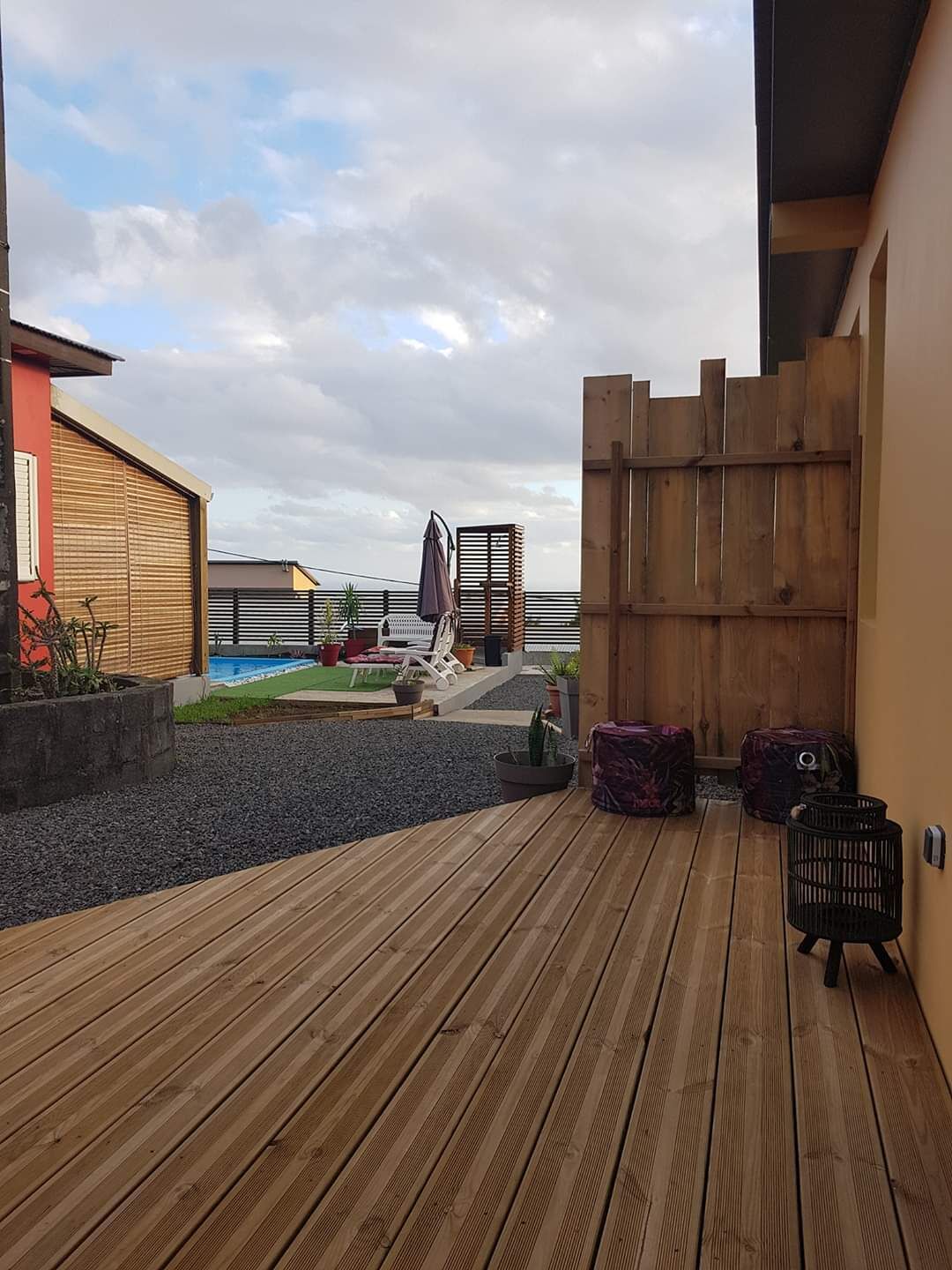 A wooden deck with a pool, potted plants, and a wooden fence.