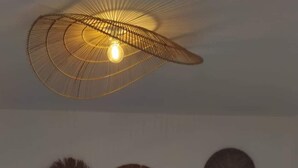 A bedroom with a large bed, a hanging light fixture, and decorative wall art. - La Kazanou (Saint-Joseph)