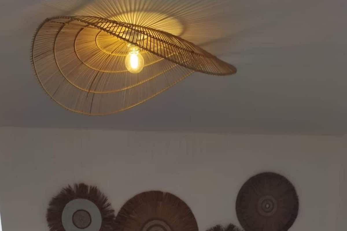 A bedroom with a large bed, a hanging light fixture, and decorative wall art.