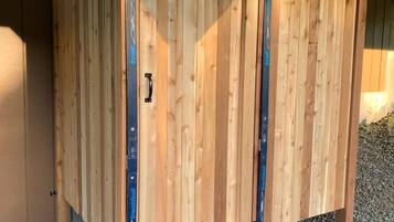 A wooden structure with a door, possibly a shed or storage unit, with metal supports and a handle.