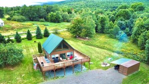 A cabin with a deck, a small shed, and a fire pit area.