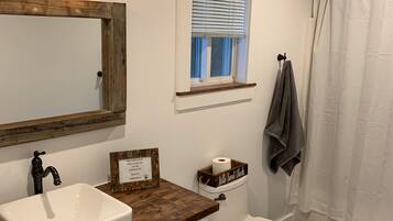 Een bad/douchecombinatie, een haardroger, handdoeken, zeep