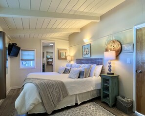 Relax in this inviting bedroom with a large bed, bedside table, and mounted television.