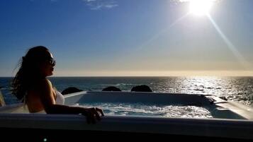 Una persona en una bañera con vistas al océano y al atardecer.
