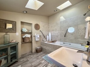 Bathroom features a bathtub, vanity, and skylight.