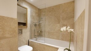 Een badkamer met een bad, toilet en een spiegel.