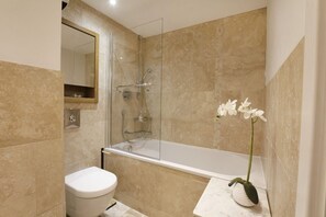 A bathroom with a bathtub, toilet, and a mirror. - The Abbott's Chambers (York)