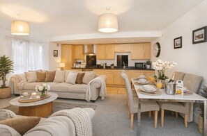 A modern living room with a sofa, coffee table, and dining area with a table set for two.