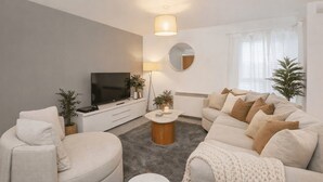 Een moderne woonkamer met een bank, een salontafel, een televisie en een spiegel.