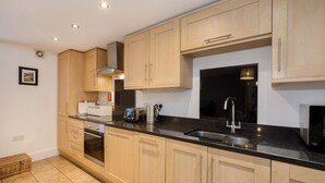 Een keuken met houten kastjes, een zwart aanrecht, roestvrijstalen apparatuur en een spoelbak.