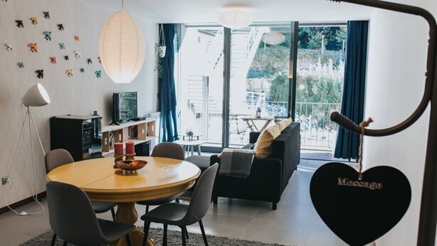 Ein modernes Wohnzimmer mit einem runden Esstisch, einer Couch und einem Balkon mit Blick.