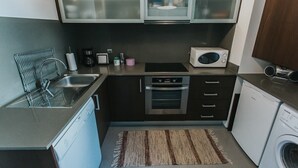 Eine kompakte Küche mit Geschirrspüler, Backofen, Mikrowelle und Waschmaschine.