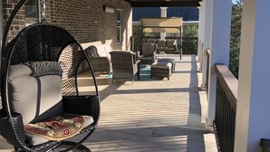 A covered outdoor patio with wicker furniture and a ceiling fan. - Newly Built House Close to Masters (Evans)