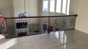 A spacious, well-lit interior with a polished floor, a wooden railing, and a large window providing natural light. - Newly Built House Close to Masters (Evans)