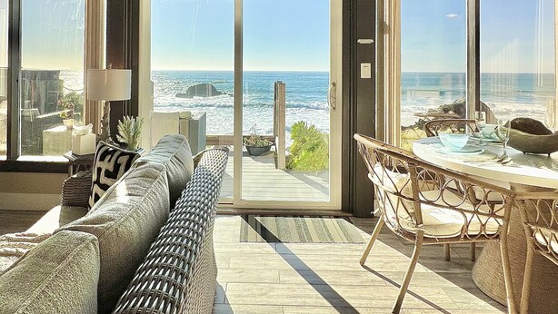A spacious living area with a large sliding glass door leading to a balcony overlooking the ocean. - Seamist Beach Cottage (Bodega Bay)