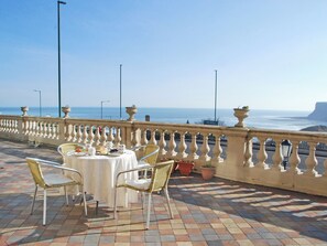 Une terrasse avec une table dressée pour deux personnes, donnant sur la mer.