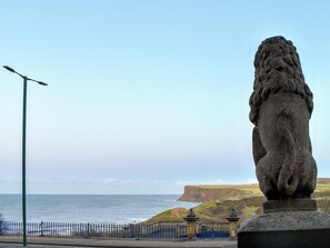 Une vue sur la côte, avec une statue de lion en pierre, un lampadaire et une clôture.