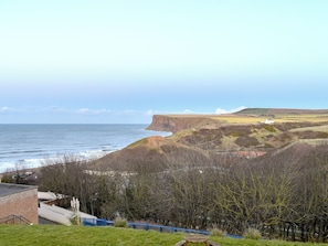 A coastal landscape with cliffs, a body of water, and a building with a fenced area. - 2 bedroom accommodation in Saltburn-by-the-Sea (Saltburn-by-the-Sea)