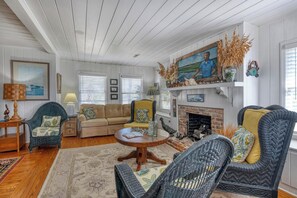 A cozy living room with a fireplace, comfortable seating, and a large painting above it. - Miller Villa, 6 bedroom, 3 bathrooms, deep water channel (Murrells Inlet)