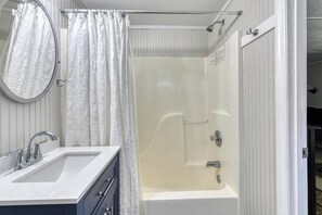 A bathroom with a bathtub, a sink, and a shower curtain. - Miller Villa, 6 bedroom, 3 bathrooms, deep water channel (Murrells Inlet)