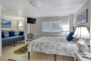 A bedroom with a bed, a television, a window with blinds, a chair, and a rug. - Miller Villa, 6 bedroom, 3 bathrooms, deep water channel (Murrells Inlet)