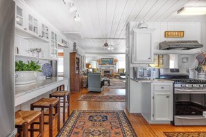 A kitchen with white cabinetry, a stove, and a dining area with a rug. - Miller Villa, 6 bedroom, 3 bathrooms, deep water channel (Murrells Inlet)
