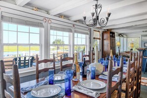A dining area with a view of the outdoors, featuring a table set with plates, glasses, and a bottle. - Miller Villa, 6 bedroom, 3 bathrooms, deep water channel (Murrells Inlet)