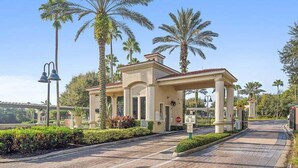 A building with a covered entrance, palm trees, and a paved pathway.