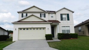 A two-story house with a garage, a front yard, and a driveway. - 5/4 Pool Home With THREE Master Suites In Coveted Windwood Bay Community (Davenport)