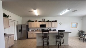 A modern kitchen with a central island, stainless steel appliances, and light wood cabinetry. - 5/4 Pool Home With THREE Master Suites In Coveted Windwood Bay Community (Davenport)