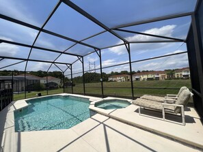 Une piscine extérieure couverte, dotée de chaises longues, d’un jacuzzi et offrant une vue sur les immeubles résidentiels.