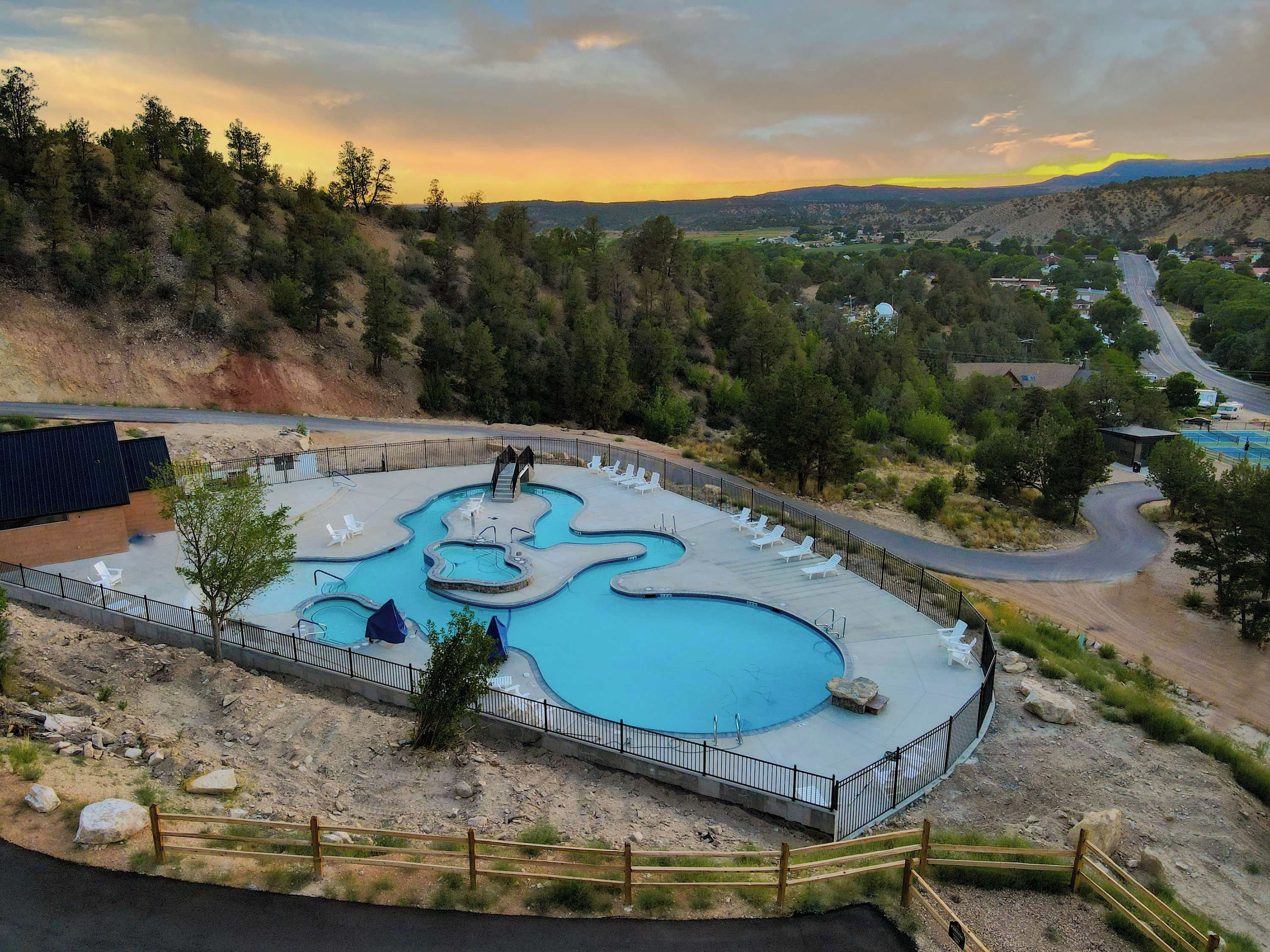 A swimming pool with a unique design, surrounded by a fence and a wooden walkway.