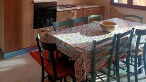 Una cocina con armarios de madera, microondas, estufa y una mesa de comedor con sillas.