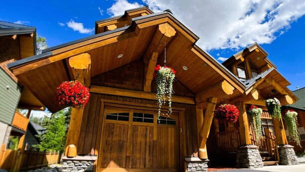 Une cabane en bois avec une grande porte de garage, des marches en pierre et des jardinières suspendues.