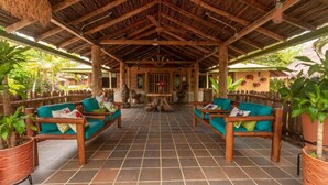 A covered outdoor seating area with wooden furniture and potted plants. - Samadhi Ecohotel by Rotamundos (Puerto Escondido)